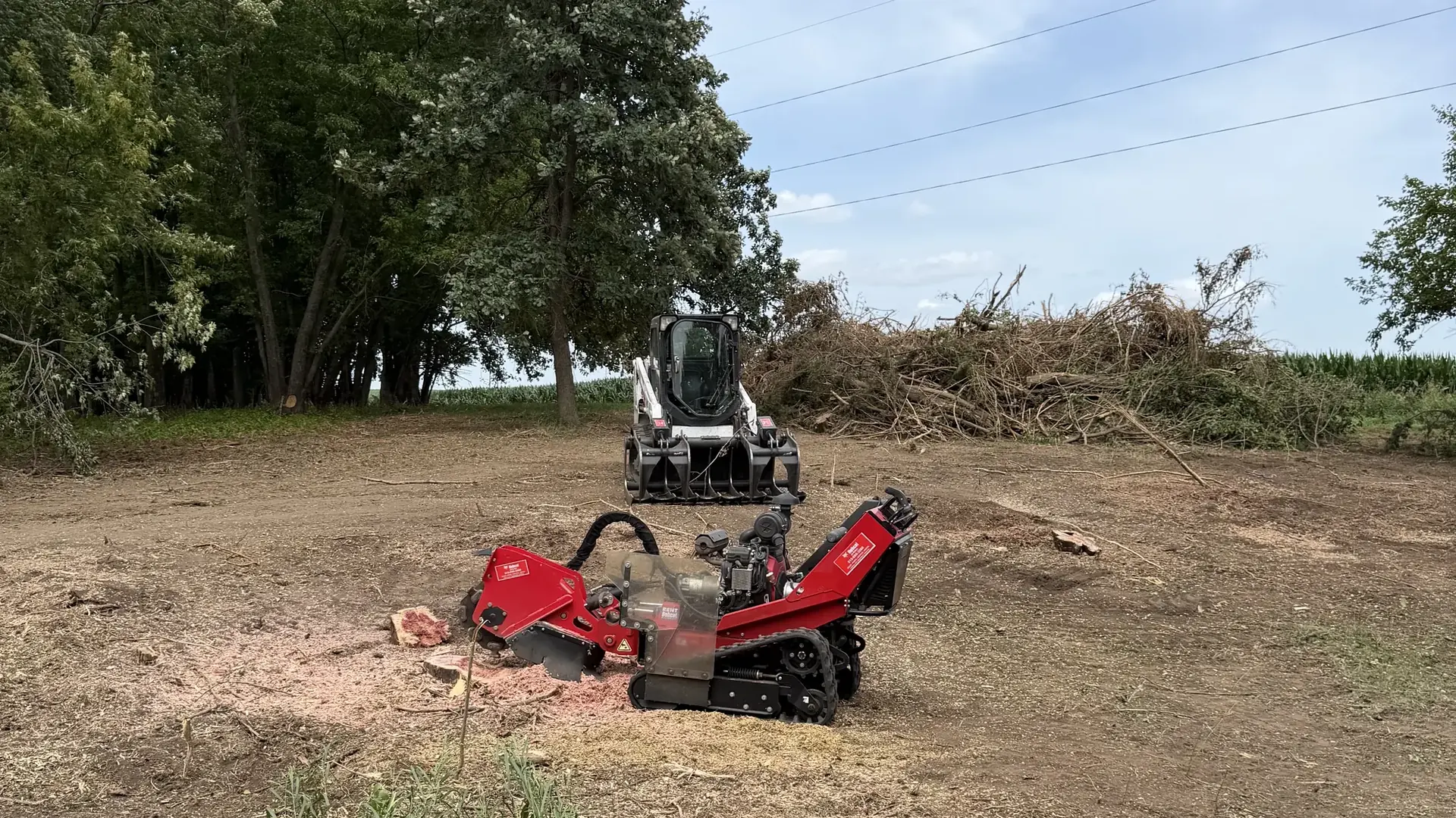 Red tracked mulcher and skid steer on freshly cleared ground