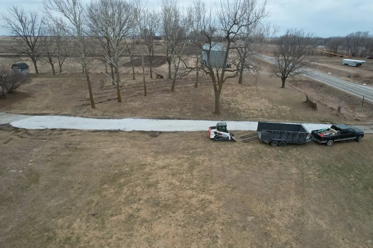 Aerial view of a new gravel driveway with skid steer and dump trailer